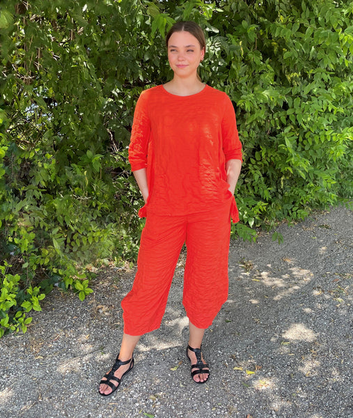 model in a wide leg chili orange color pant with a tapered ankle, worn with a matching top
