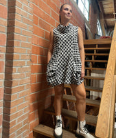 model in a black and white textured plaid sleeveless tunic with an oversized cowl neck, princess seams and pockets set into the side seams
