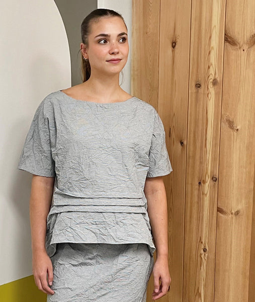 model in grey and white pinstripe pullover tee with horizontal pintucks at the waist