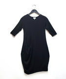 black tunic with a curved hip pocket set into a diagonal seam across the body