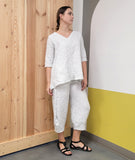 model in a white and black dot print pullover top with a vneck, 3/4 sleeves and pockets sewn into the side seams with matching tulip shaped pants