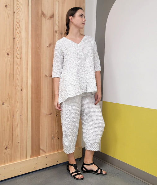 model in a white and black dot print pullover top with a vneck, 3/4 sleeves and pockets sewn into the side seams with matching tulip shaped pants