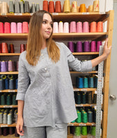 model in a grey and white pinstripe tunic length top with squared hip pockets, 3/4 sleeves and large square buttons down the placket