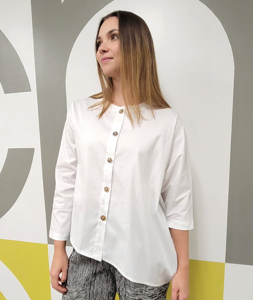model in a black and white striped pant with an asymmetrical button down white blouse with one batwing sleeve