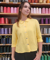 model in a butter color button down blouse with 3/4 sleeves and a black pant