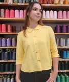 model in a butter color button down blouse with 3/4 sleeves and a black pant