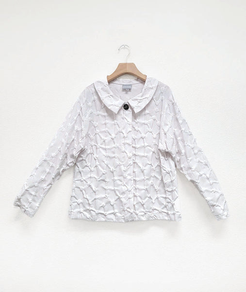 button down blouse with long sleeves and a rounded collar, with a hidden placket with a single visible top button.  fabric is white with a pinched circle texture