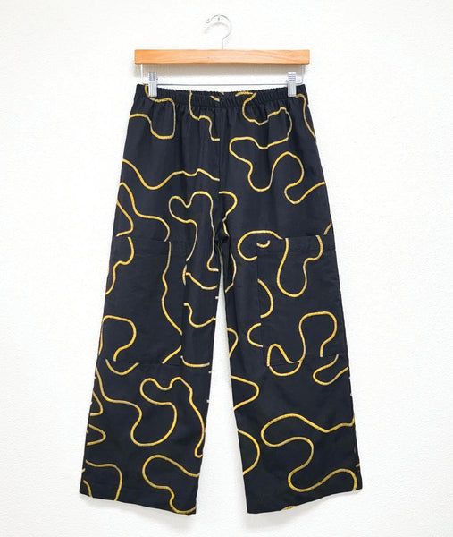 wide leg black pant with a yellow swirl pattern embroidered all over. pant has a full elastic waistband with dropped cargo pockets