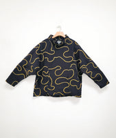 black cotton pullover top with a yellow swirl embroidered all over. blouse has long sleeves, a short boxy body, and a cowl neck