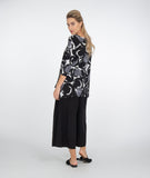 model in a black pant with a black and white circle print top