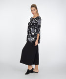 model in a black pant with a black and white circle print top