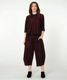 model in a boxy button down blouse with a 3/4 sleeve and twinbutton detail. fabric is striped with varying shades of red. worn with a wide leg matching pant with oversized pockets