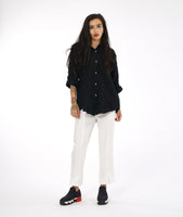 model in a slim leg white pant with a center front seam and a small split at the ankle. worn with a textured black button down blouse with rolled sleeves and a black and white button