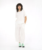 model in a boxy white textured top with a matching pant. pant has a tulip shaped silhouette with a tuck detail at the center front seams, and elastic waistband and pockets