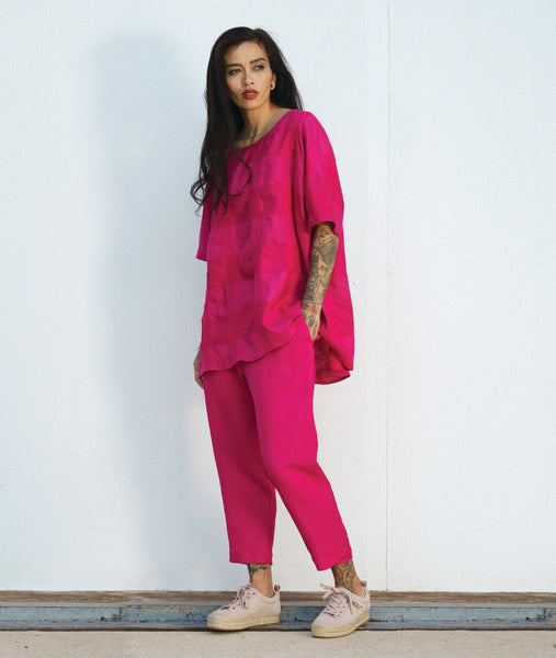 model in a hot pink cropped slim pant, with an oversized hot pink checkered pullover top