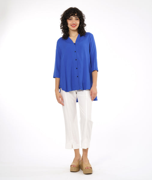 model in a slim cut white pant with a center front seam and ankle split, worn with a periwinkle button down blouse with a 3/4 sleeve, rounded high-low hem and a short mandarin collar