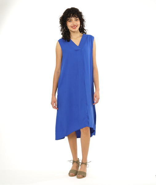 model in a periwinkle sleeveless dress with a v neck and center seam. hem is just below the knee, a-line silhouette with pockets at the hip side seams