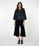 model in a boxy button down jacket with a 3/4 sleeve and portrait collar. fabric is striped with varying shades of blues. worn with a wide leg black pant
