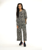 model in a black and white print straight leg pant with a matching button down blouse with a wide rounded collar and a 3/4 sleeve