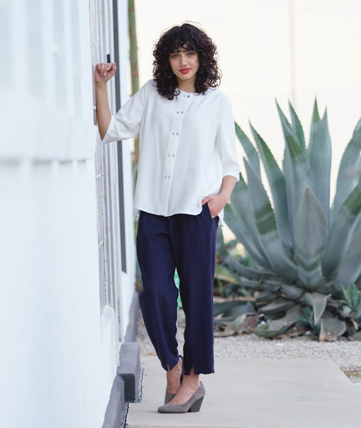 model in a blue straight leg pant with a white collar-less button down blouse