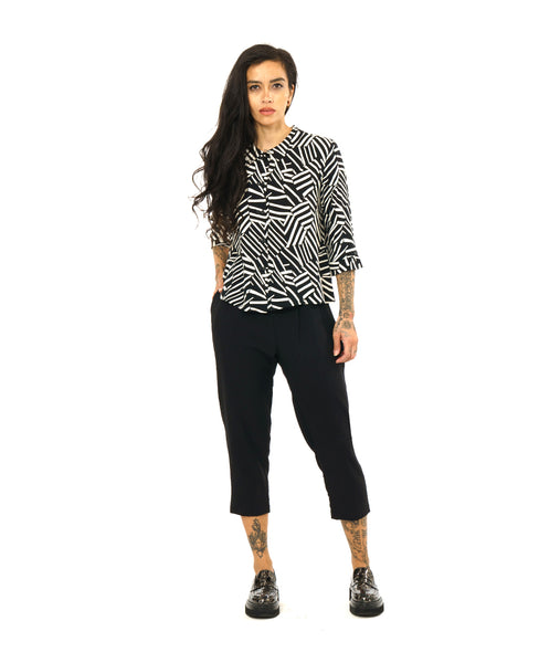 model in a black and white print button down blouse with a twin button detail, worn with a cropped black pant