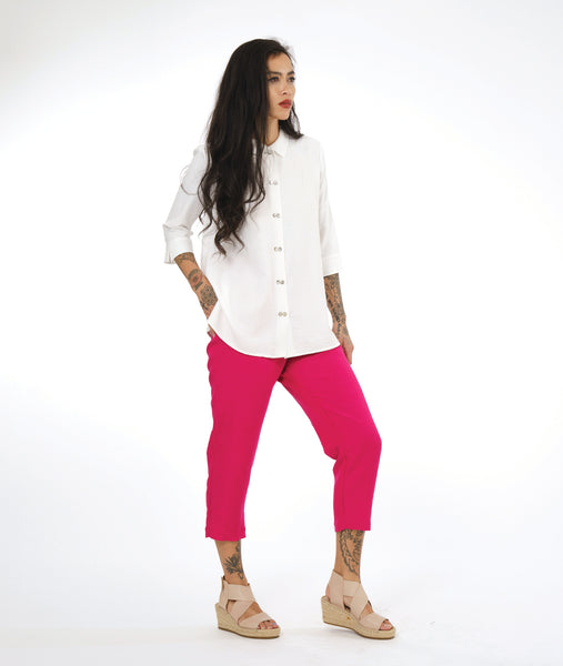 model in a hot pink cropped pant with a white button down blouse with a twin button detail and 3/4 sleeves