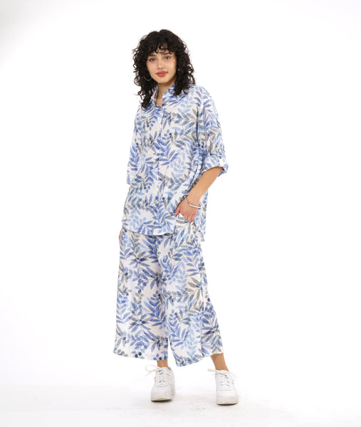 model in a wide leg pant with a split on either leg, with a matching button down blouse with rolled sleeves in a matching blue and black leaf print on a white background