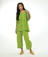 model in a wide leg lime pant with a tulip shaped silhouette, and a matching lime pullover top with a large rounded neckline, elbow length raglan sleeve, and a large checkered print woven into the fabric