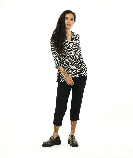 model in a slim black crop pant with a black and white broken stripe print top with 3/4 sleeves, a v-neck, side splits and a center front seam