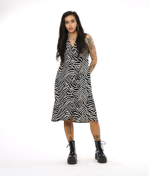 model in a black and white broken stripe sleeveless dress with a v-neck, pockets in the side seams, and a split at the bottom of the front center seam