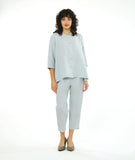 model in a slim cropped silvery blue pant with a boxy matching button down blouse with a 3/4 sleeve and a small meandering collar