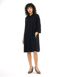 model in a black shirt dress with elbow length sleeves and black twin buttons half way down the dress front center