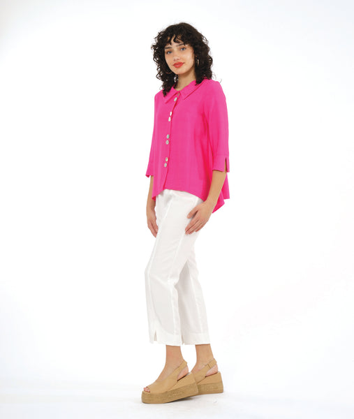 model in a slim white pant, worn with a hot pink button down blouse with a vertical twinbutton detail, 3/4 sleeves, and a dipped hem at either hip