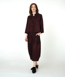 model in a boxy button down jacket with a 3/4 sleeve and portrait collar. fabric is striped with varying shades of red. worn with a wide leg matching pant with oversized pockets