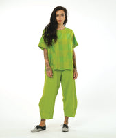 model in a wide tulip shaped lime green pant with a tapered ankle, worn with a matching top in a extra large grid print with a round collar, short sleeves, two squared hip pockets and a buttoned packet up the back