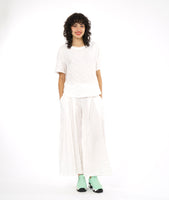 boxy white pullover top with a matching white pant with a wide leg and deep vertical tucks at the waist