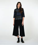 model in a button down blouse with a 3/4 sleeve with a split cuff, a double collar and striped print in varying shades of blue. worn with a wide leg black pant