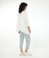 model in a slim leg blue-grey cropped pant, worn with a white pullover top with a single hip pocket, 3/4 sleeves, a dipped him at either hip and a rounded neckline. Top has an extra large grid print woven in to it