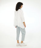 model in a slim leg blue-grey cropped pant, worn with a white pullover top with a single hip pocket, 3/4 sleeves, a dipped him at either hip and a rounded neckline. Top has an extra large grid print woven in to it