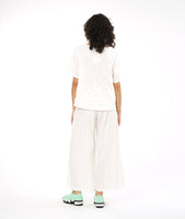 boxy white pullover top with a matching white pant with a wide leg and deep vertical tucks at the waist