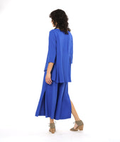 model in a periwinkle pullover top with a round neckline, 3/4 sleeves, and a rounded high-low hem with a flowy godet in the back. worn with a matching wide leg pant with a tall split along the side seam