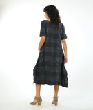 model in a large check print dress with an asymmetrical body, round neckline, elbow length sleeves, and contrasting panels across the body