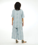 model in a silvery blue large grid print wide leg pant with a matching pullover top with a raglan sleeve