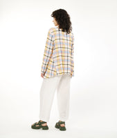 model in a wide leg white pant with a multicolor plaid top with a dipped hem on either hip and rolled sleeves