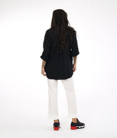 model in a slim leg white pant with a center front seam and a small split at the ankle. worn with a textured black button down blouse with rolled sleeves and a black and white button