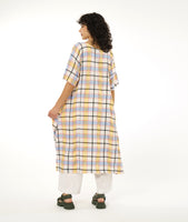 model in a midi length multi-color plaid dress with a short sleeve, rounded neckline and a contrasting hip pocket, worn over a pair of wide leg white pants