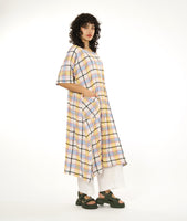 model in a midi length multi-color plaid dress with a short sleeve, rounded neckline and a contrasting hip pocket, worn over a pair of wide leg white pants