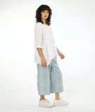 model in a large grid print silvery blue wide leg pant, with a matching white pullover top with a dipped hem on either side, 3/4 sleeves and a single hip pocket
