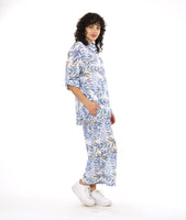 model in a wide leg pant with a split on either leg, with a matching button down blouse with rolled sleeves in a matching blue and black leaf print on a white background