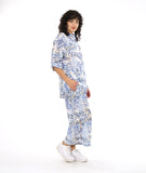 model in a wide leg pant with a split on either leg, with a matching button down blouse with rolled sleeves in a matching blue and black leaf print on a white background